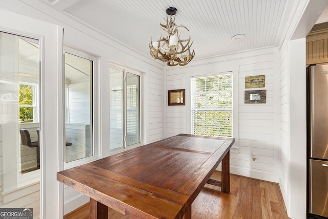 dining space featuring hardwood / wood-style flooring, wooden walls, and plenty of natural light