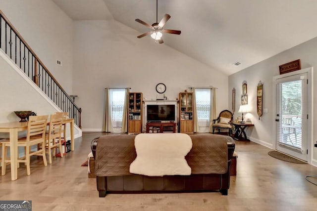 living room with high vaulted ceiling, ceiling fan, and light hardwood / wood-style flooring