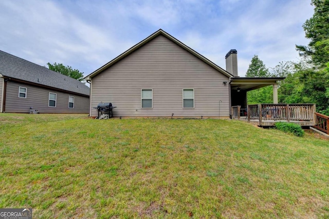 rear view of property featuring a lawn and a wooden deck