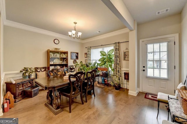 dining area with a notable chandelier, ornamental molding, and hardwood / wood-style floors