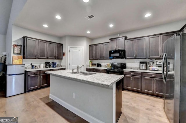 kitchen with black appliances, light hardwood / wood-style floors, a kitchen island with sink, and sink