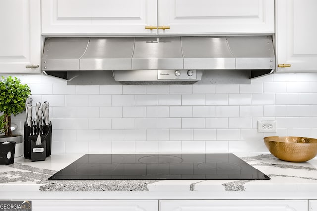 room details featuring backsplash, black electric stovetop, white cabinets, and range hood