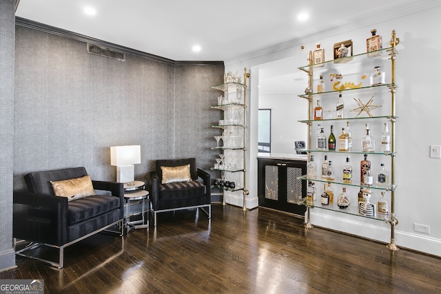 sitting room featuring ornamental molding, hardwood / wood-style floors, and bar area