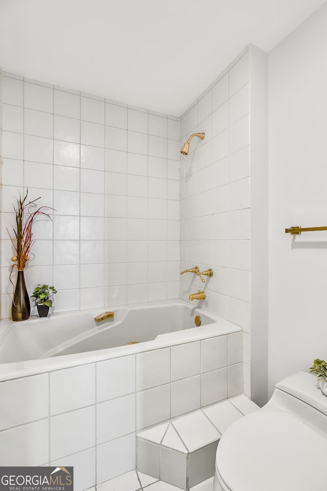 bathroom with tiled shower / bath combo and toilet