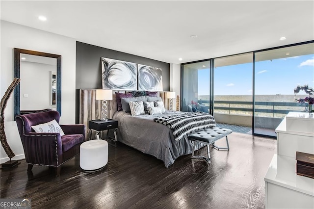 bedroom featuring access to exterior, a wall of windows, hardwood / wood-style flooring, and a water view