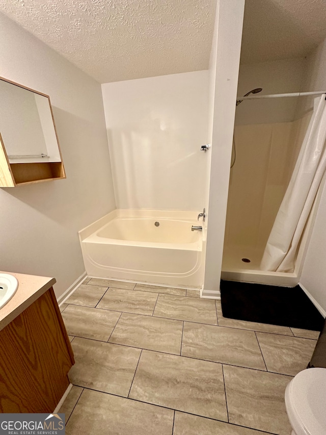 full bathroom featuring toilet, vanity, a textured ceiling, and separate shower and tub