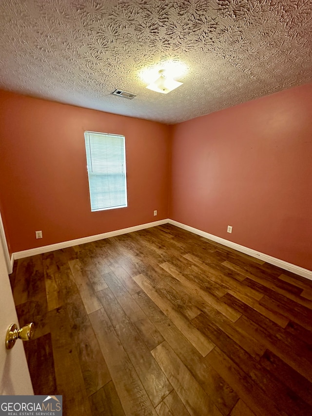 spare room with wood-type flooring and a textured ceiling