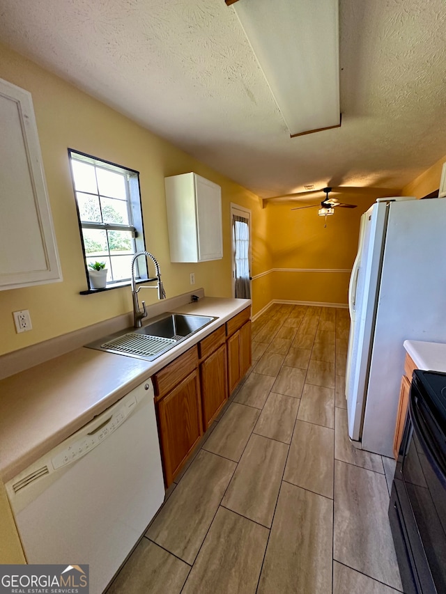 kitchen featuring a textured ceiling, white appliances, sink, and white cabinets