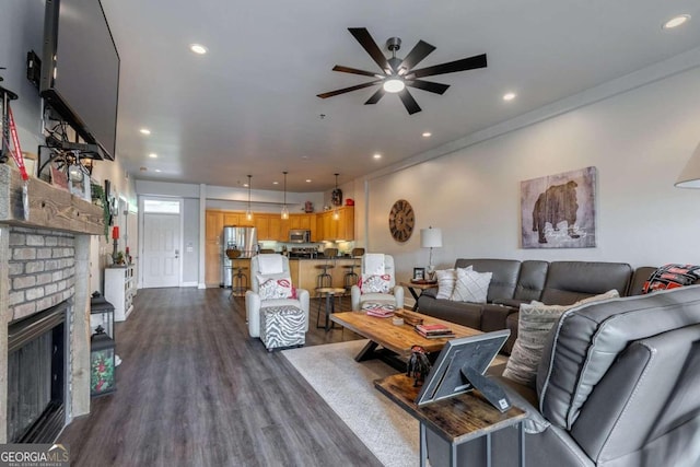 living room featuring ceiling fan, a fireplace, crown molding, and dark hardwood / wood-style flooring