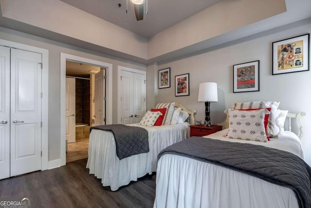 bedroom with ceiling fan, multiple closets, and dark hardwood / wood-style floors