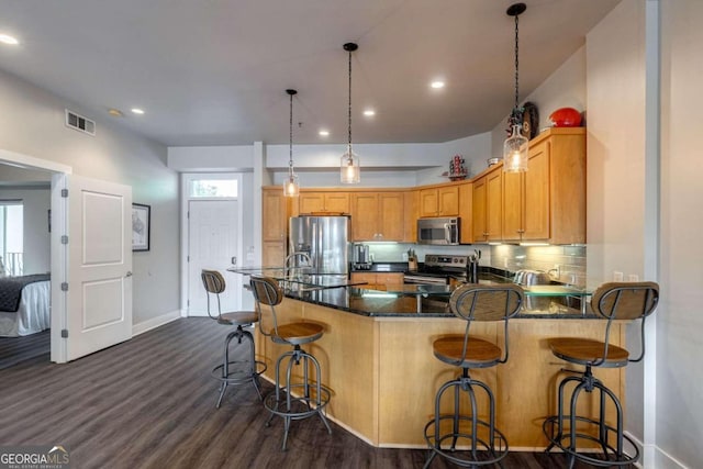 kitchen featuring pendant lighting, tasteful backsplash, a kitchen breakfast bar, stainless steel appliances, and dark hardwood / wood-style flooring