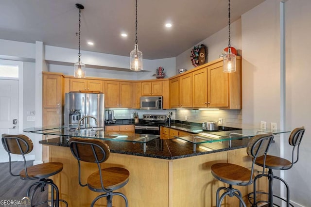 kitchen with backsplash, stainless steel appliances, hanging light fixtures, and a kitchen breakfast bar