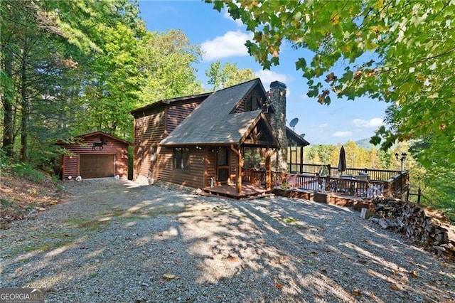 cabin with a wooden deck, an outbuilding, and a garage