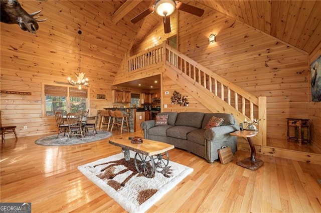 living room featuring wood walls, light wood-type flooring, and high vaulted ceiling