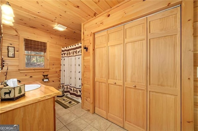 bathroom featuring vanity, wooden walls, tile patterned flooring, a shower with shower curtain, and wood ceiling