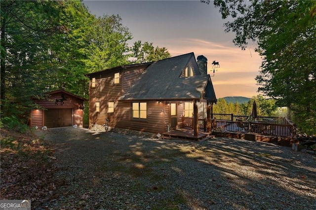 exterior space with a garage, a deck, and an outbuilding