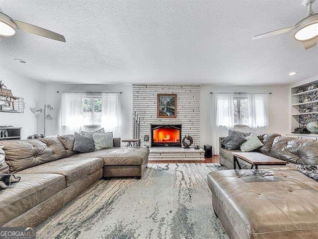 living room with carpet flooring, a textured ceiling, a fireplace, and ceiling fan