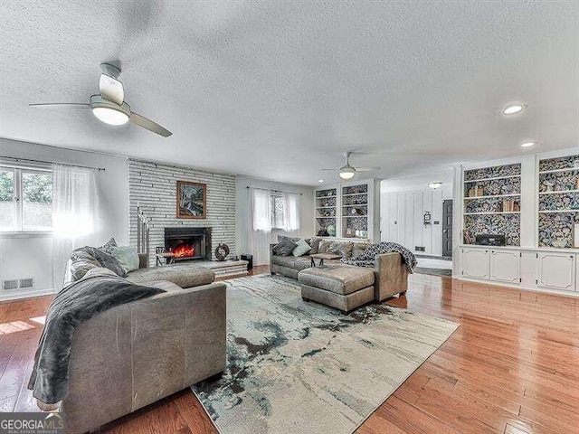 living room featuring a textured ceiling, a fireplace, and light hardwood / wood-style floors