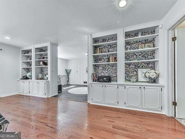 bar with white cabinets, a textured ceiling, and light hardwood / wood-style floors