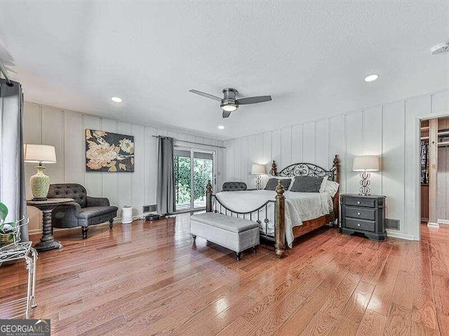 bedroom featuring light hardwood / wood-style flooring, ceiling fan, access to outside, and a textured ceiling