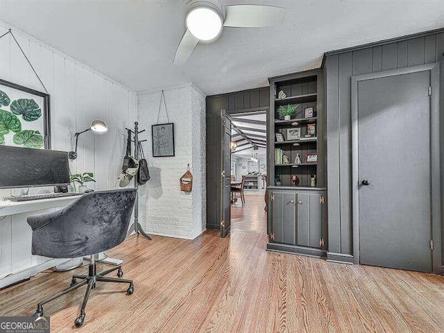 office featuring ceiling fan, wooden walls, and light hardwood / wood-style floors