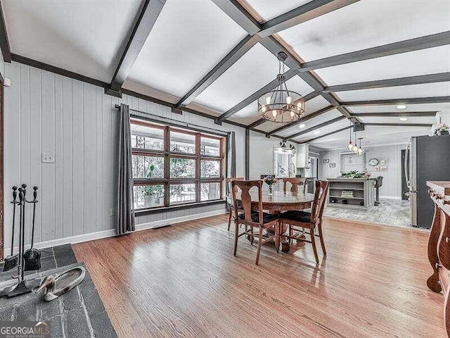 dining area with lofted ceiling with beams, light hardwood / wood-style floors, and a chandelier