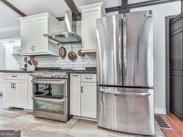 kitchen featuring white cabinets, wall chimney exhaust hood, stainless steel appliances, crown molding, and decorative backsplash