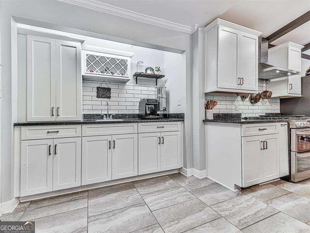 kitchen with white cabinetry, tasteful backsplash, wall chimney exhaust hood, stainless steel range with gas cooktop, and sink