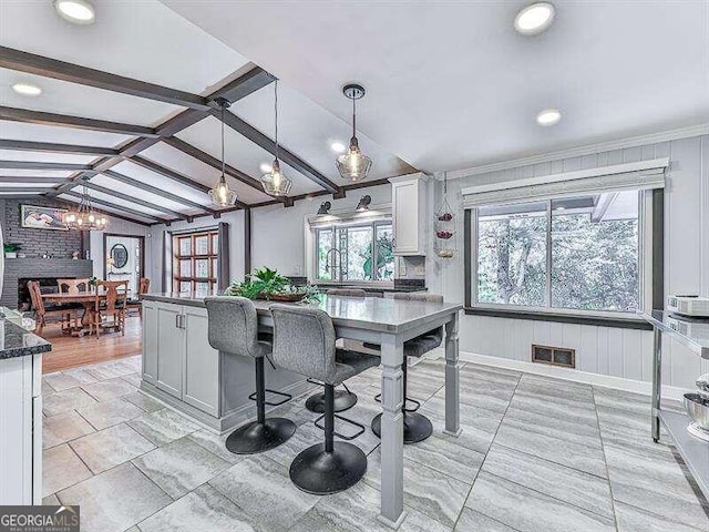 kitchen with vaulted ceiling with beams, white cabinets, decorative light fixtures, a chandelier, and dark stone counters