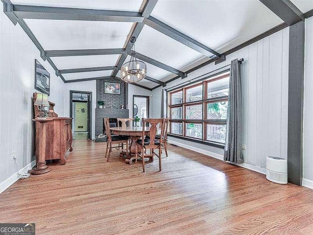 dining room featuring lofted ceiling with beams, light hardwood / wood-style floors, and an inviting chandelier