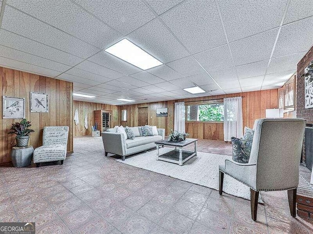 living room featuring a drop ceiling and wood walls