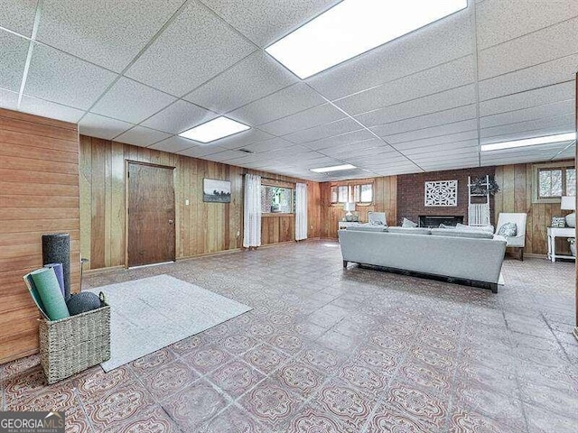 living room with a drop ceiling, wood walls, and plenty of natural light