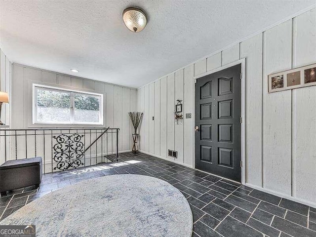 entrance foyer featuring a textured ceiling and wood walls