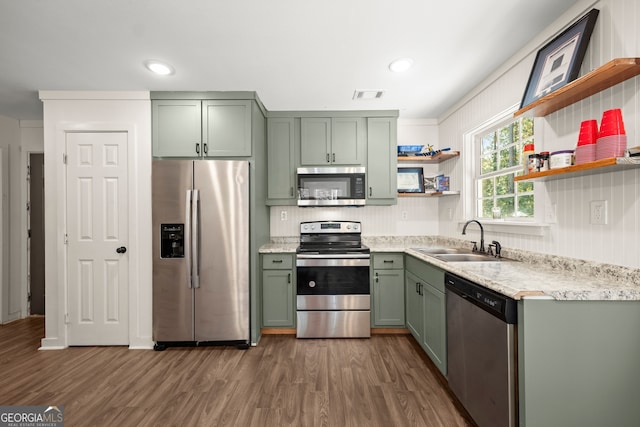 kitchen with green cabinetry, stainless steel appliances, sink, and dark hardwood / wood-style flooring