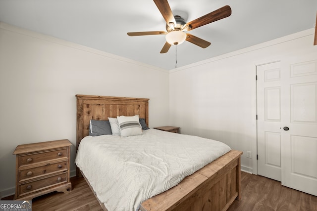 bedroom with ornamental molding, ceiling fan, and dark wood-type flooring