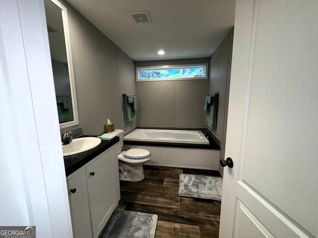 bathroom featuring a tub to relax in, hardwood / wood-style floors, vanity, and toilet