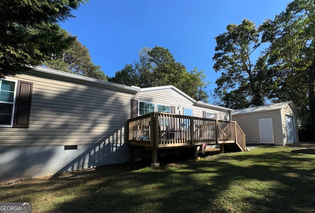 back of house featuring a lawn, a wooden deck, and a shed