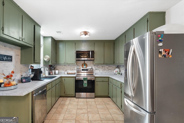 kitchen featuring appliances with stainless steel finishes, green cabinets, and decorative backsplash