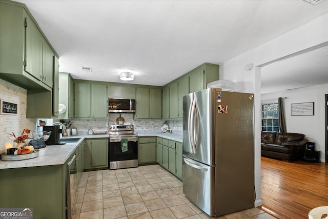 kitchen with sink, appliances with stainless steel finishes, light wood-type flooring, and green cabinets