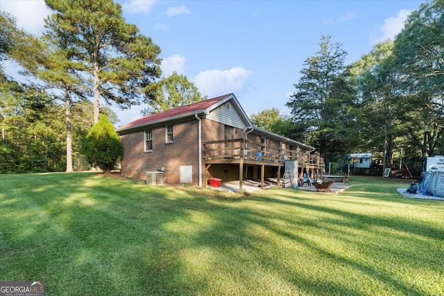 rear view of house with a lawn, central air condition unit, and a wooden deck