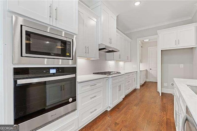 kitchen featuring stainless steel appliances, crown molding, dark wood-type flooring, and white cabinetry