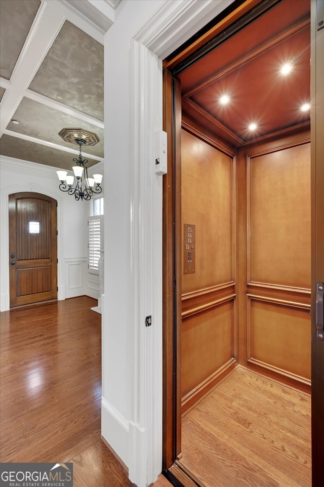 details featuring crown molding, elevator, an inviting chandelier, and hardwood / wood-style flooring