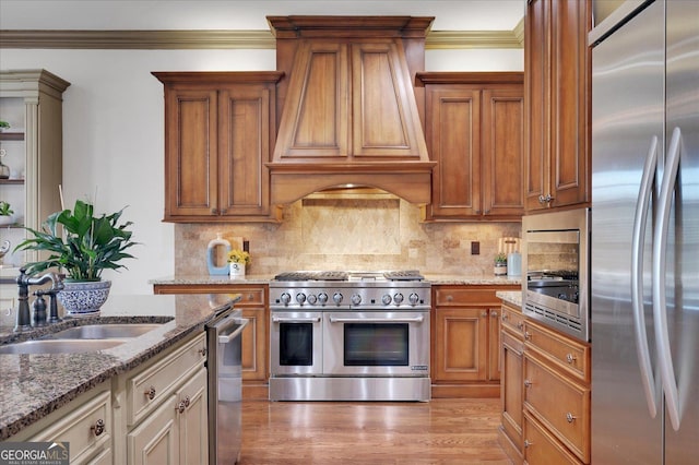 kitchen featuring brown cabinetry, crown molding, light stone counters, arched walkways, and stainless steel appliances