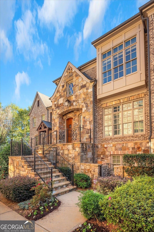 view of front of property with stairway and stone siding