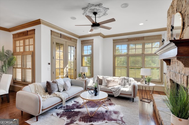 living room featuring a fireplace, wood-type flooring, ornamental molding, and ceiling fan