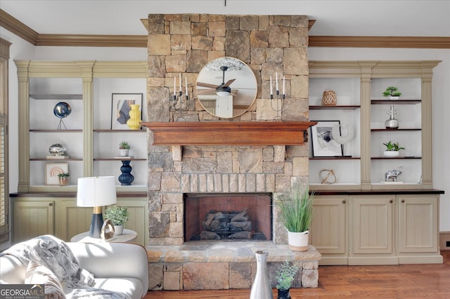 living room featuring a fireplace, ornamental molding, built in shelves, and light wood-type flooring