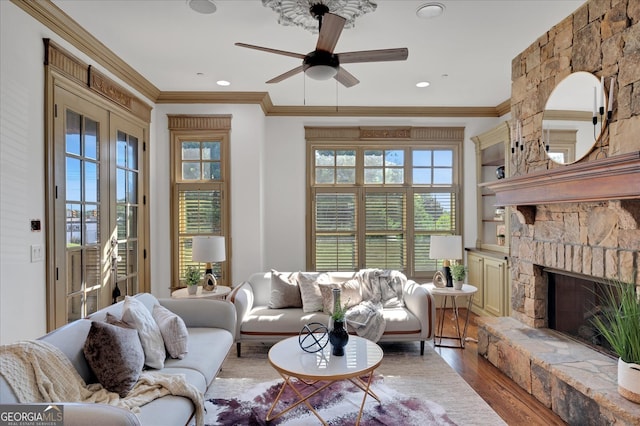 living room with hardwood / wood-style flooring, crown molding, ceiling fan, and a fireplace