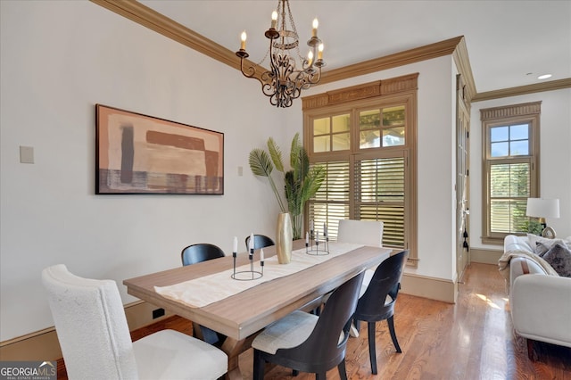 dining space featuring wood-type flooring, crown molding, and a notable chandelier