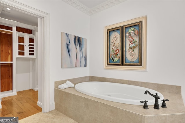 bathroom with ornamental molding, hardwood / wood-style floors, and tiled bath