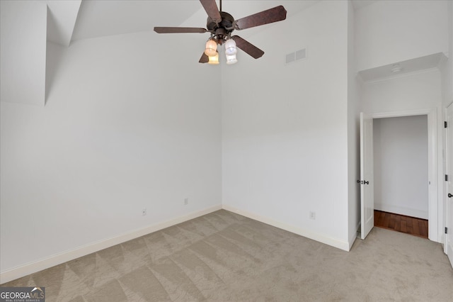 empty room featuring light colored carpet, high vaulted ceiling, and ceiling fan